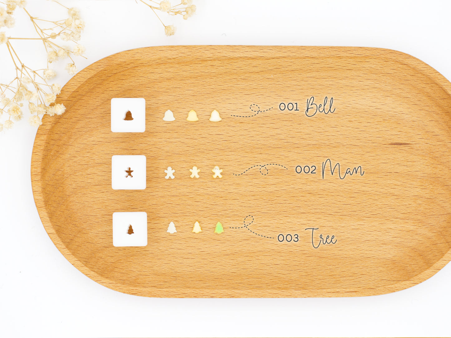 Three small square 1:12 scale clay cutters displayed next to the clay shapes they produce: a bell, a gingerbread man, and a tree.