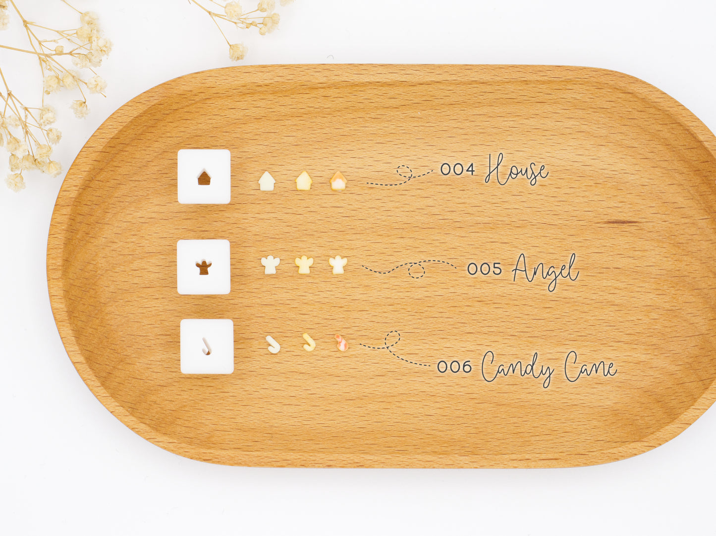 Three small square 1:12 scale clay cutters displayed next to the clay shapes they produce: a house, an angel man, and a candy cane.