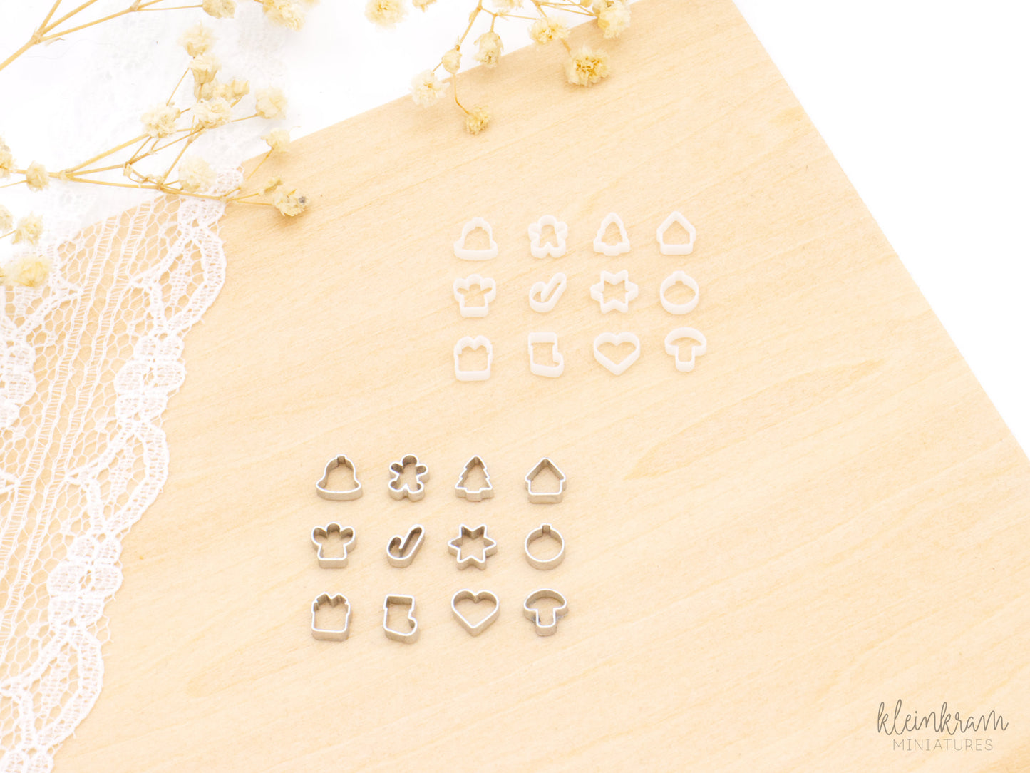 Two sets of miniature 1:12 scale christmsa deco cookie cutters: the top group shows unpainted white cutters, and the bottom group shows the same shapes painted silver. Each group includes cutters shaped like a bell, a gingerbread man, a a tree, a house, an angel, a candy cane, a star, a tree bauble, a present, a stocking, a heart and a mushroom.