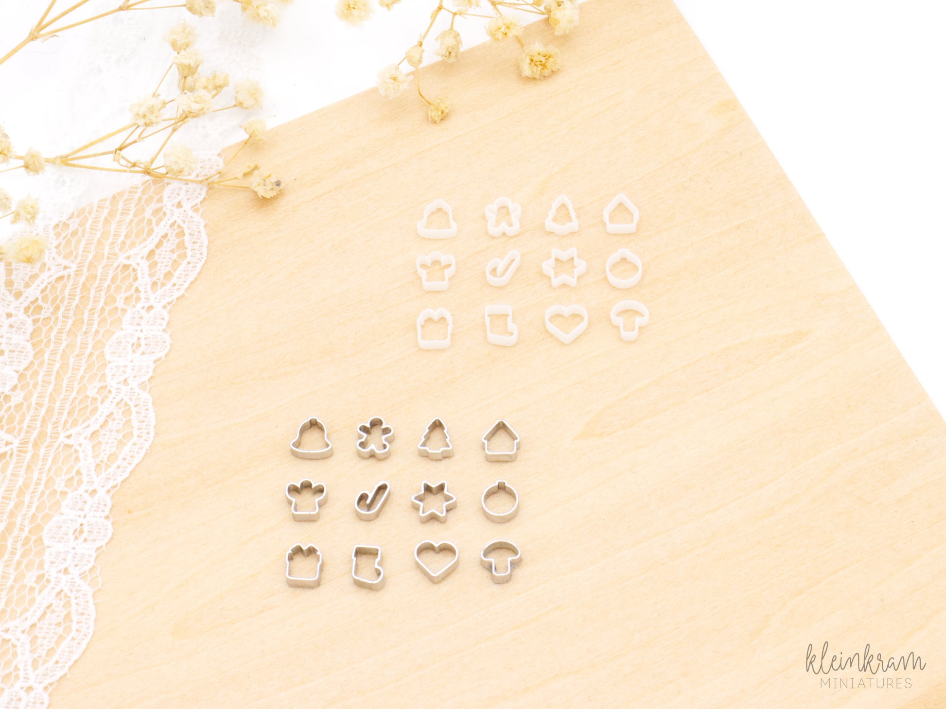 Two sets of miniature 1:12 scale christmsa deco cookie cutters: the top group shows unpainted white cutters, and the bottom group shows the same shapes painted silver. Each group includes cutters shaped like a bell, a gingerbread man, a a tree, a house, an angel, a candy cane, a star, a tree bauble, a present, a stocking, a heart and a mushroom.