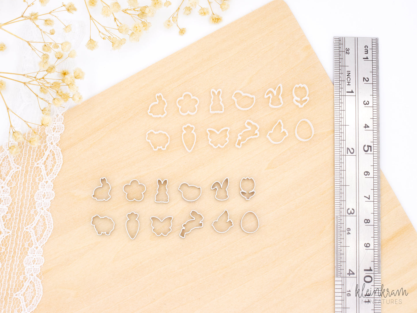 Two sets of miniature 1:6 scale easter deco cookie cutters: the top group shows unpainted white cutters, and the bottom group shows the same shapes painted silver. Each group includes cutters shaped like a bunny in profile, a flower, a standing bunny, a chick, a bunny head, a tulip, a sheep, a carrot, a butterfly, a hopping bunny, a bird, and an egg. On the right is a ruler for size reference.